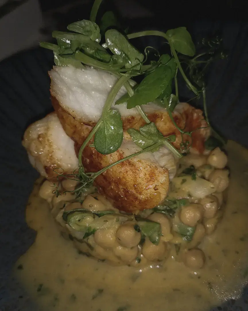 Fish with pea shoots on chickpeas in a creamy sauce