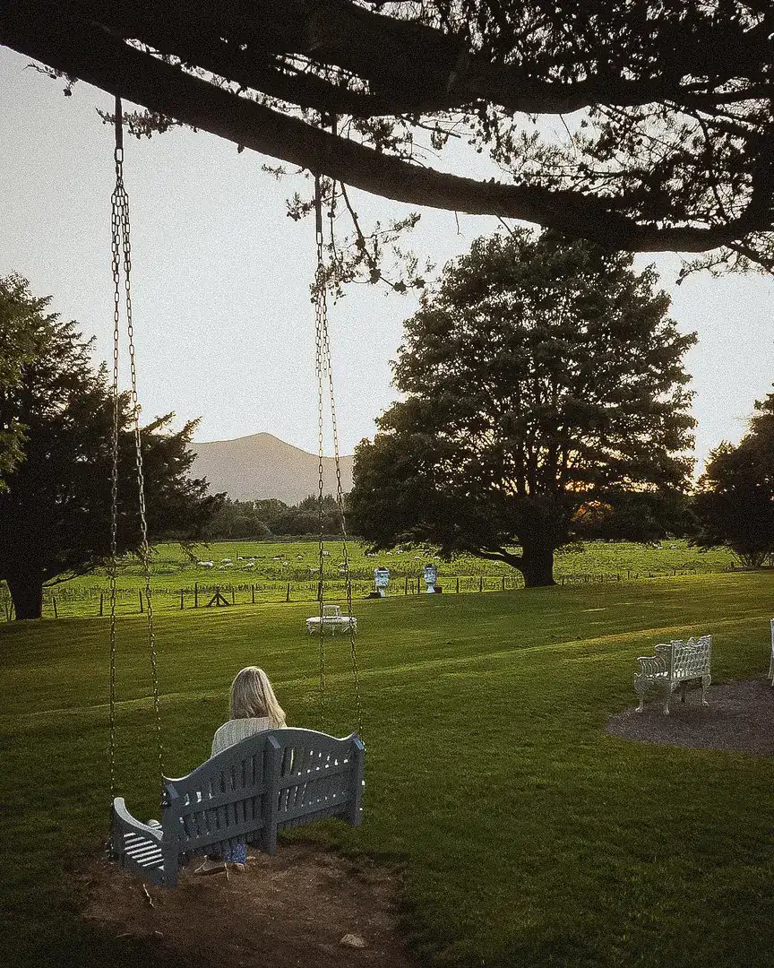 Isabelle on the blue swing bench under the cypress, mountains beyond