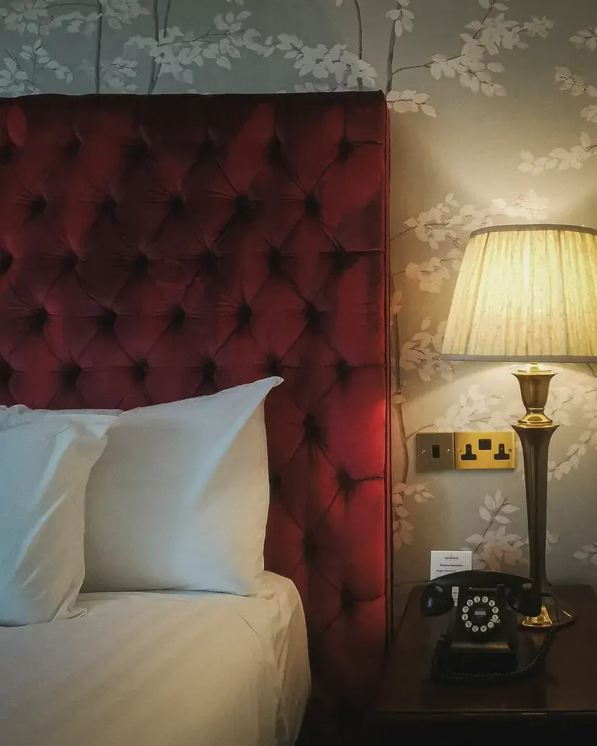Red velvet buttoned headboard, bedside lamp and rotary telephone