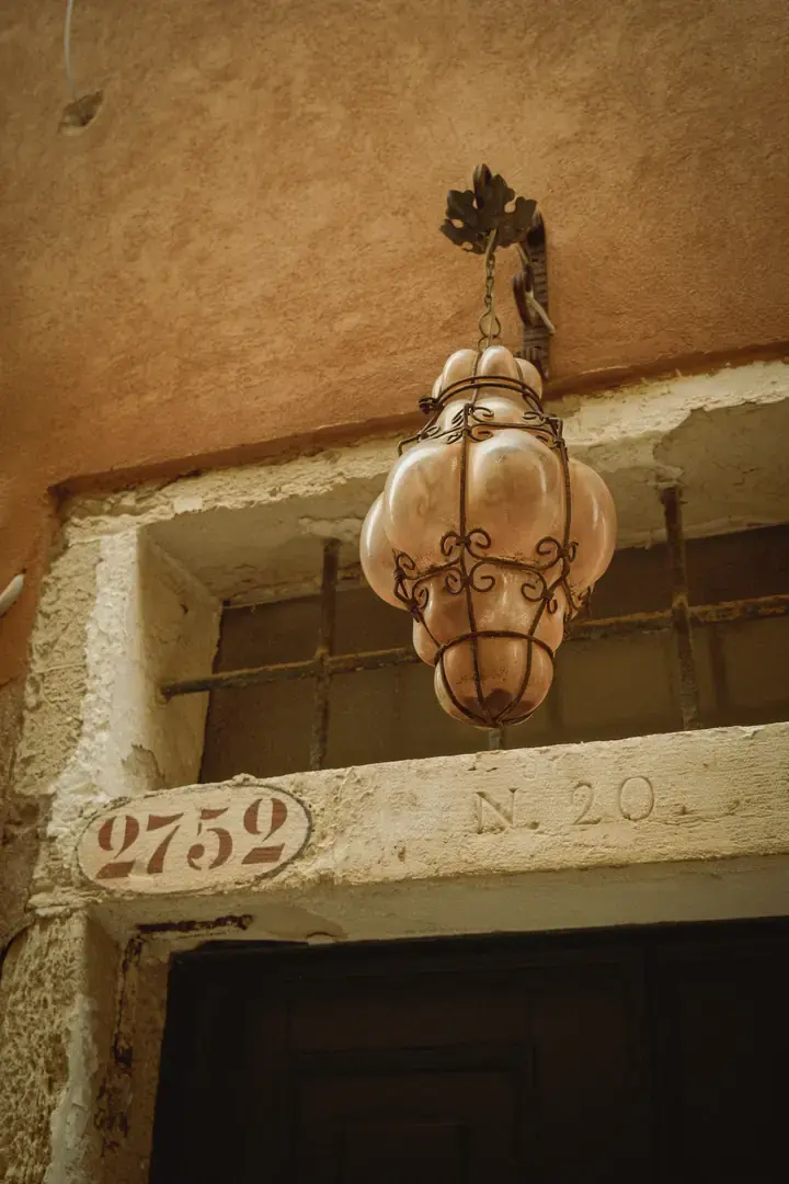 A glass lantern in a curled iron cage above a doorway marked 2752, on the calle where Novecento stands