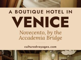 A bed with an embroidered pillow seen past ochre curtains, above the first-floor lounge at Novecento with its bookcase, fireplace and cushioned sofa